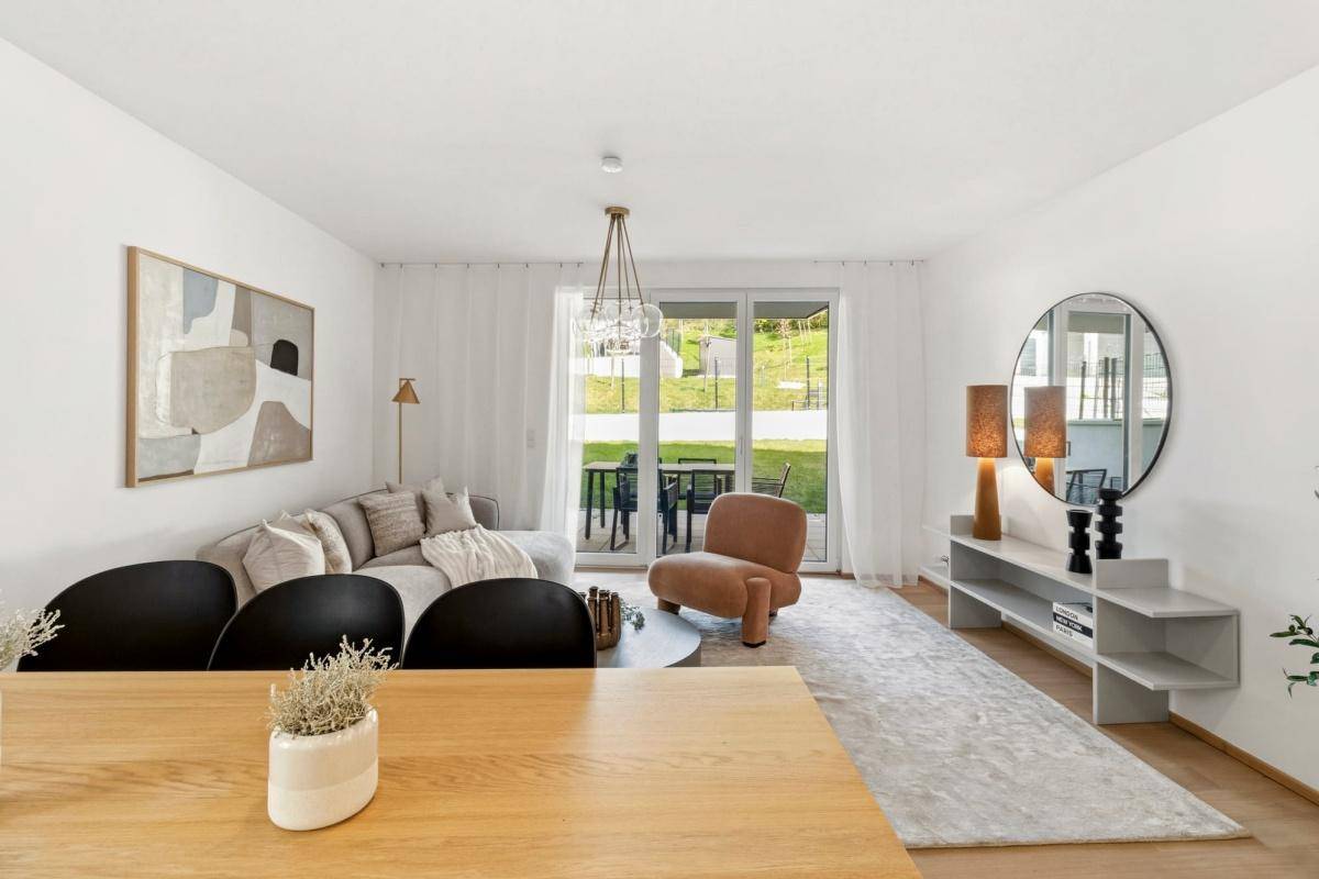 Heller, modern eingerichteter Wohn-Essbereich mit Zugang zur Terrasse und Blick ins Grüne.