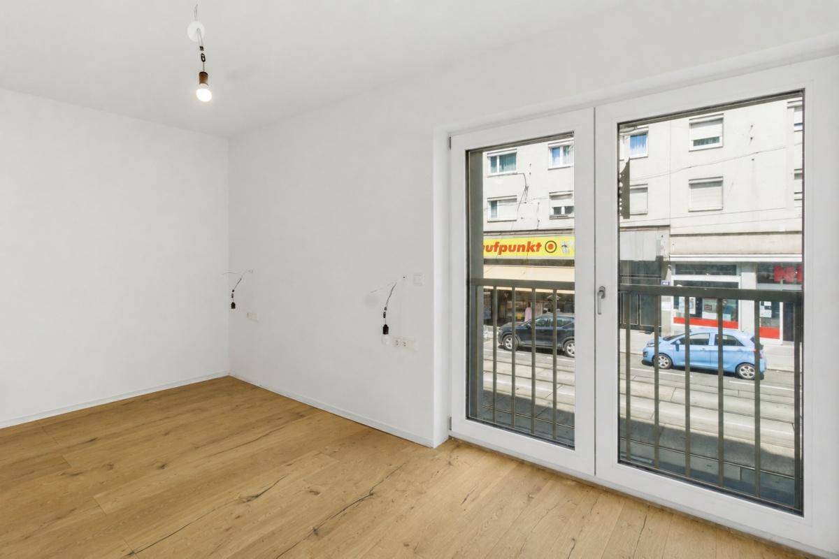 Heller Raum mit Holzboden und großem Fenster, das einen Blick auf die Straße bietet.