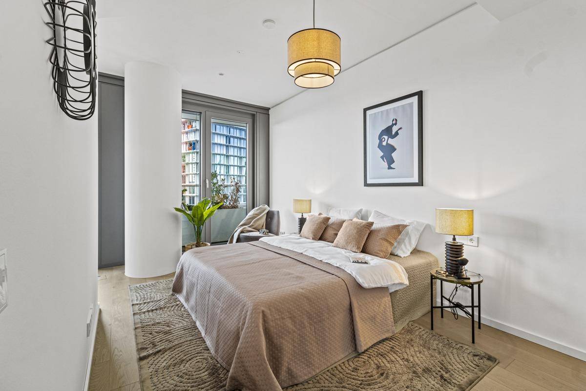 Gemütliches Schlafzimmer mit Doppelbett, Nachttischen und Blick auf die Stadt.