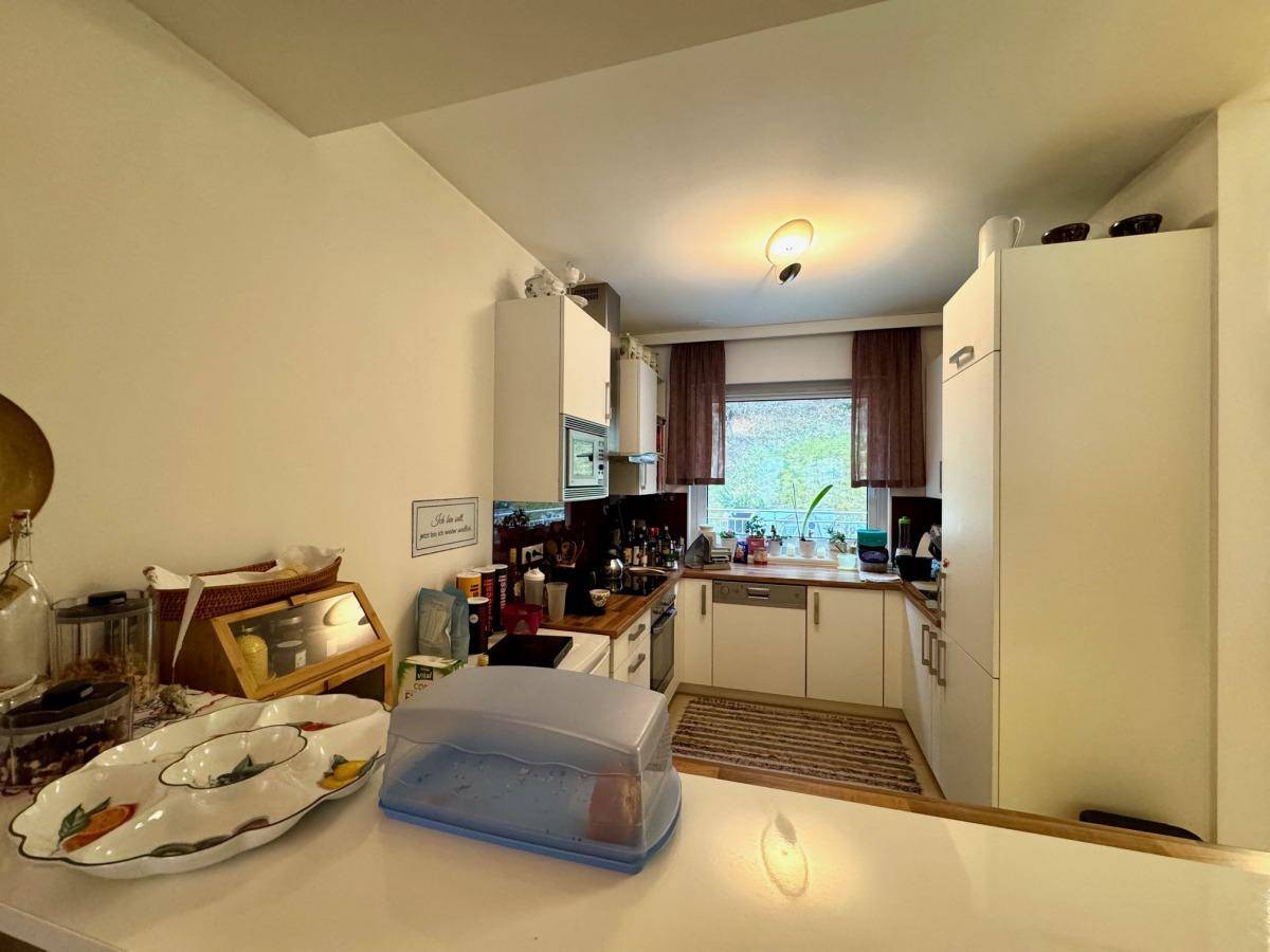 Funktionale Küche mit weißen Schränken, Holz-Arbeitsplatten und einem Fenster für natürliches Licht.
