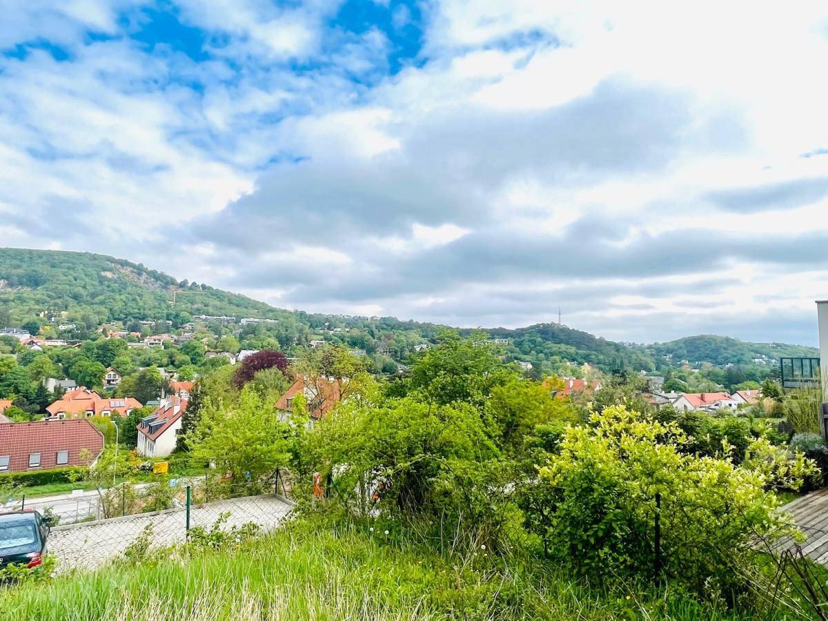 Weitläufiger Panoramablick über eine grüne Hügellandschaft mit verstreuten Häusern und einem Dorf.