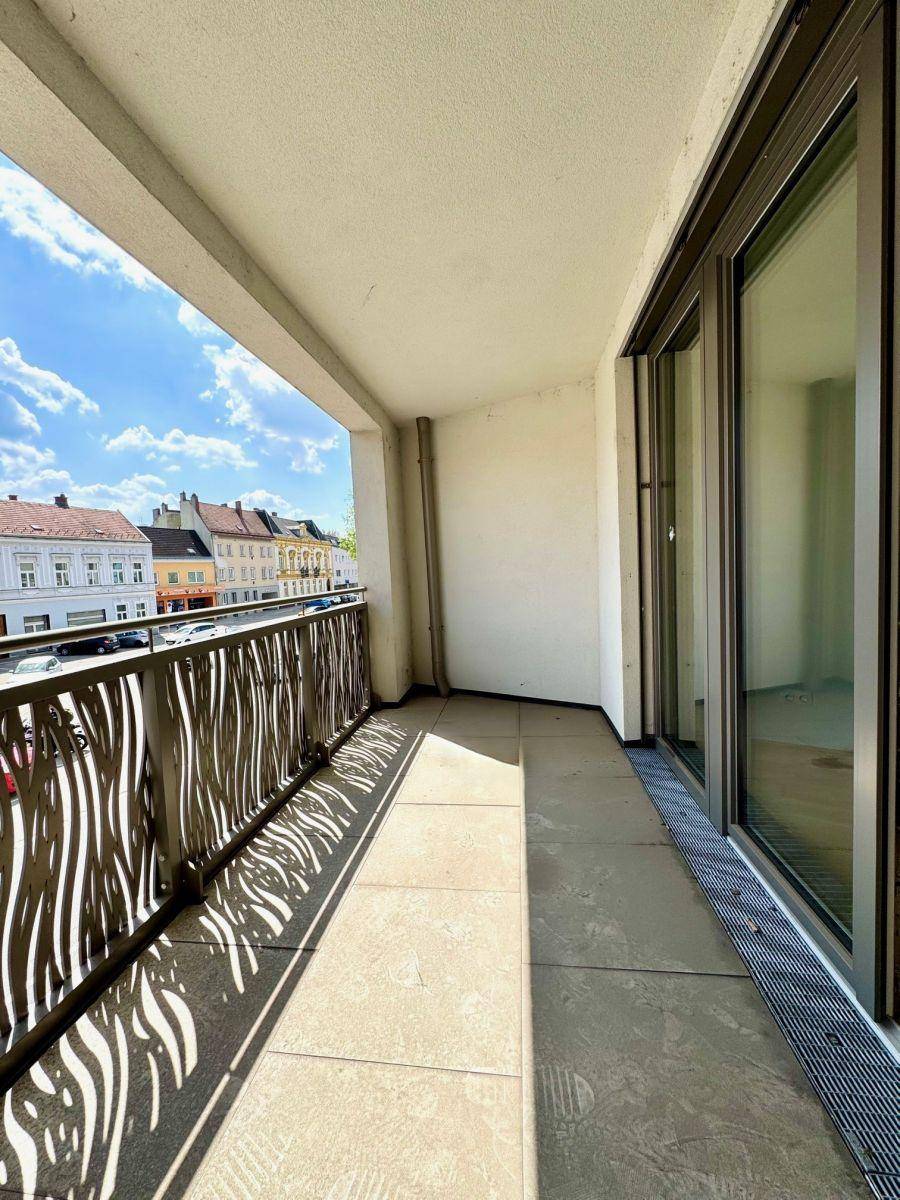 Langer Balkon mit modernem Geländer und Blick auf die umliegenden Gebäude und die Straße.