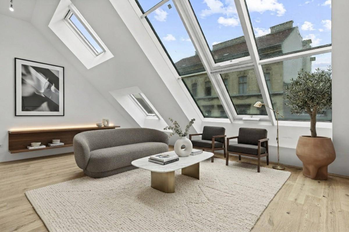 Lichtdurchflutetes Wohnzimmer mit großen Dachfenstern und Blick auf die Stadt.
