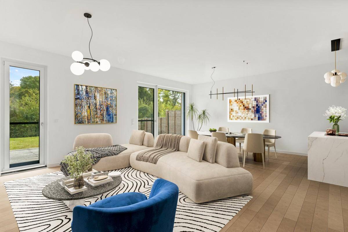 Heller, offener Wohn-Essbereich mit modernem Sofa, Holzboden und Zugang zum Garten.