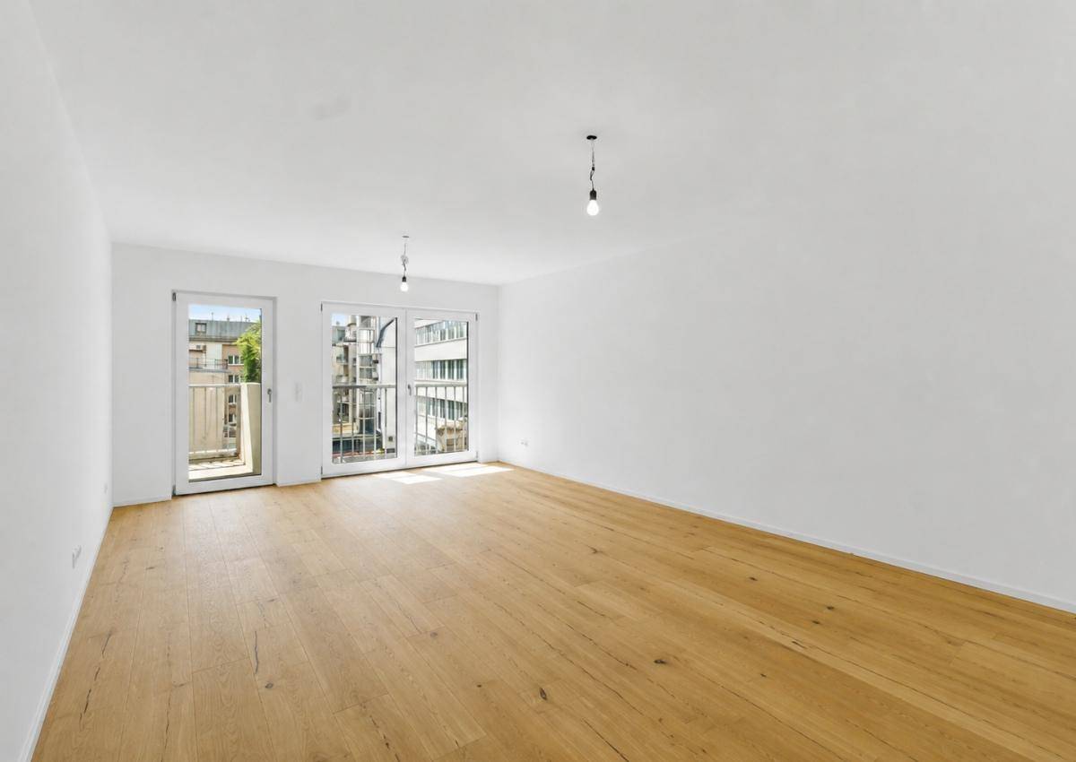 Heller Raum mit Holzboden und zwei französischen Balkonen, bereit für die individuelle Gestaltung.