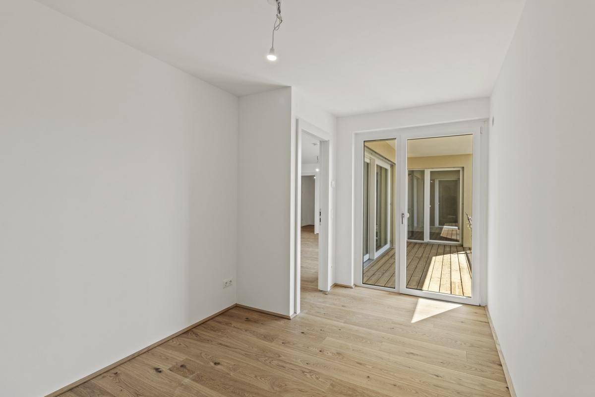 Kleinerer Raum mit Parkettboden und Zugang zu einem Balkon, ideal als Schlaf- oder Arbeitszimmer.