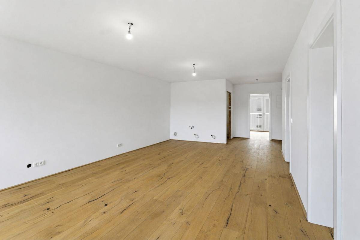 Geräumiger, heller Raum mit Holzfußboden und weißen Wänden, ideal für individuelle Gestaltung.