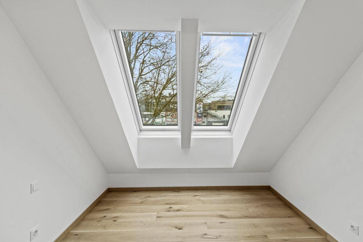 Lichtdurchflutetes Zimmer mit Holzboden und zwei großen Dachfenstern, die den Raum erhellen.