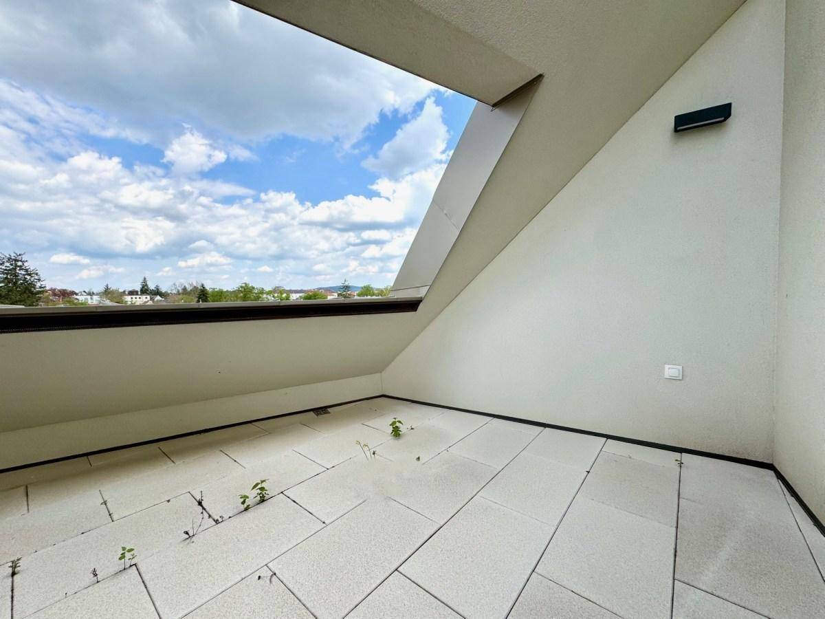 Geräumige Dachterrasse mit hellen Fliesen und einem weiten Blick auf die Umgebung und den Himmel.