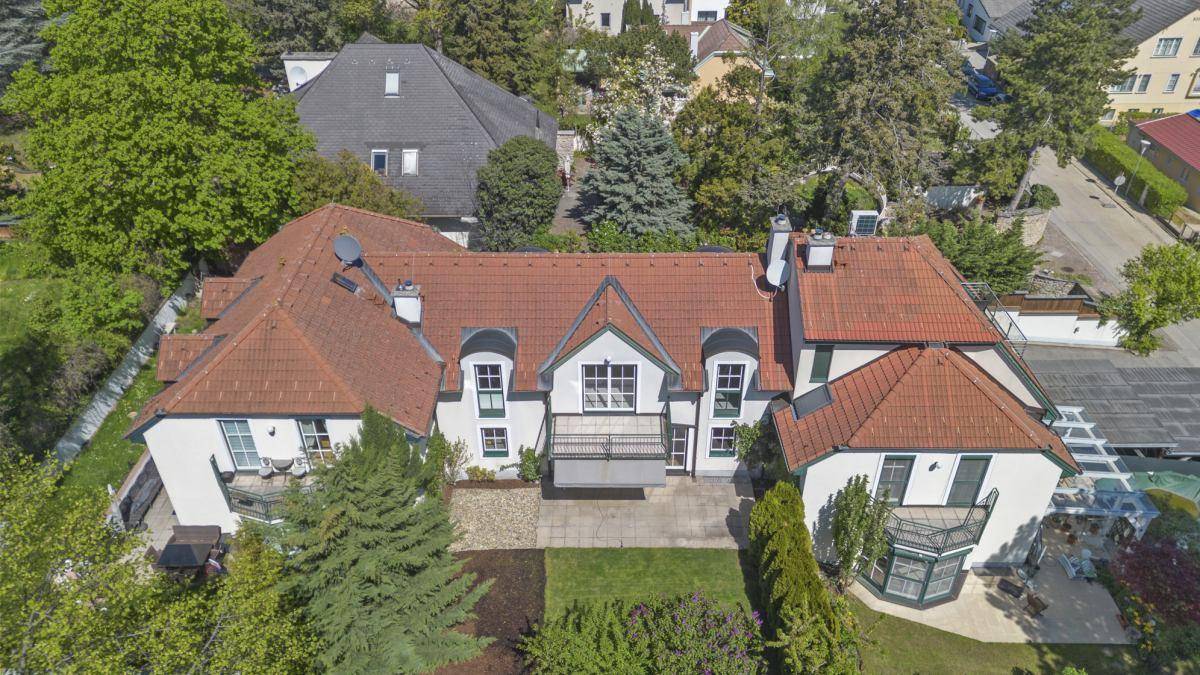Luftbild eines großen Hauses mit rotem Ziegeldach, Garten und mehreren Balkonen.