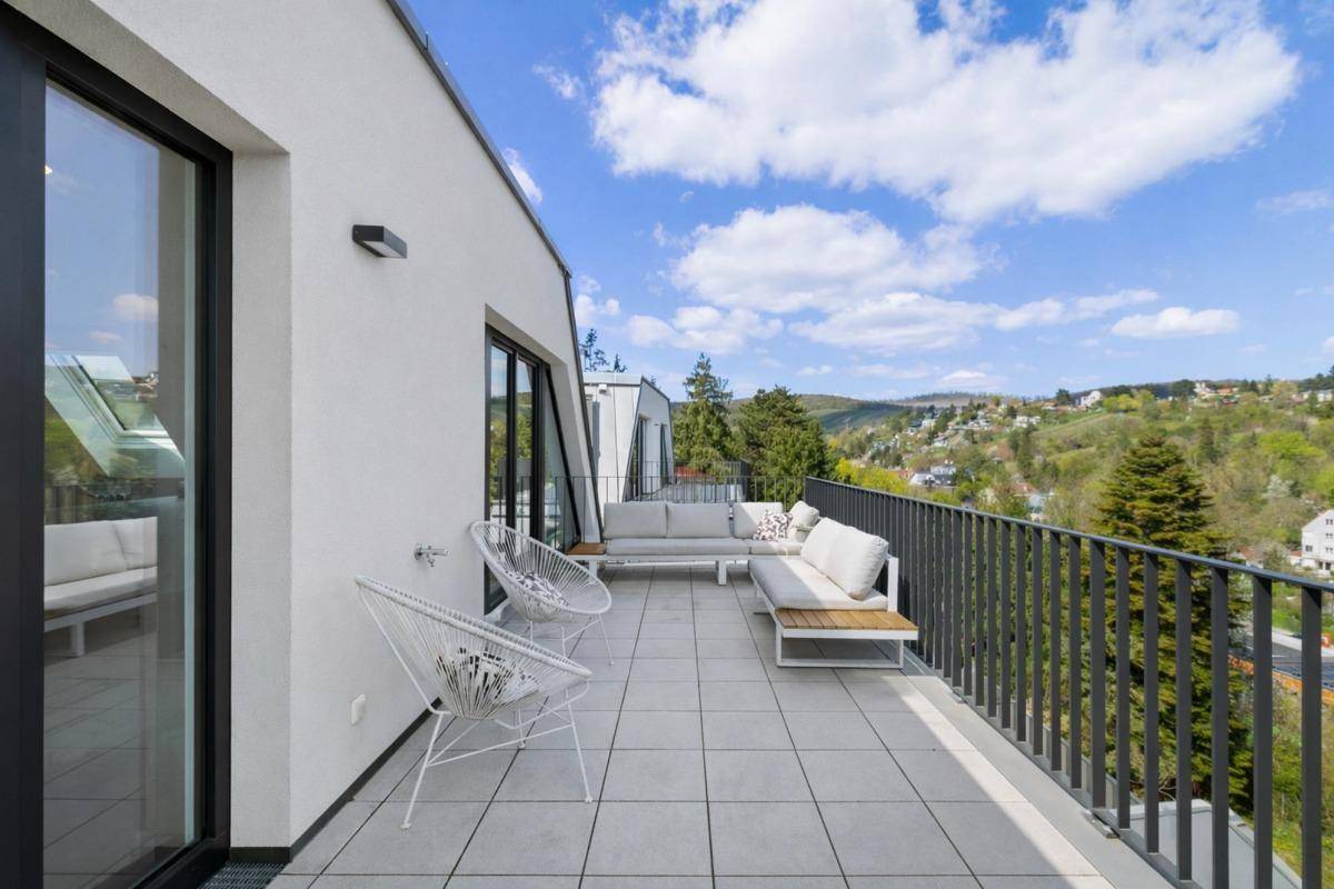 Große Terrasse mit modernen Gartenmöbeln und Panoramablick auf die grüne Umgebung und Stadt.