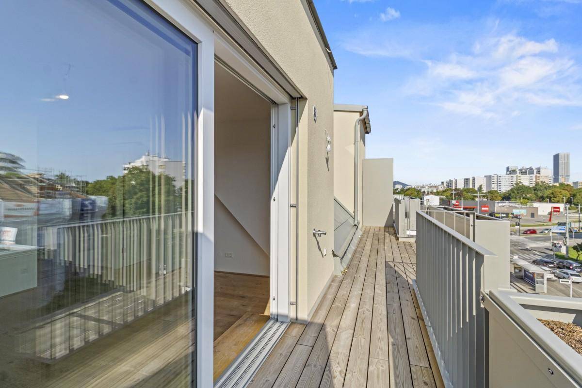 Langer Balkon mit Holzboden, Metallgeländer und Blick auf die Stadt.