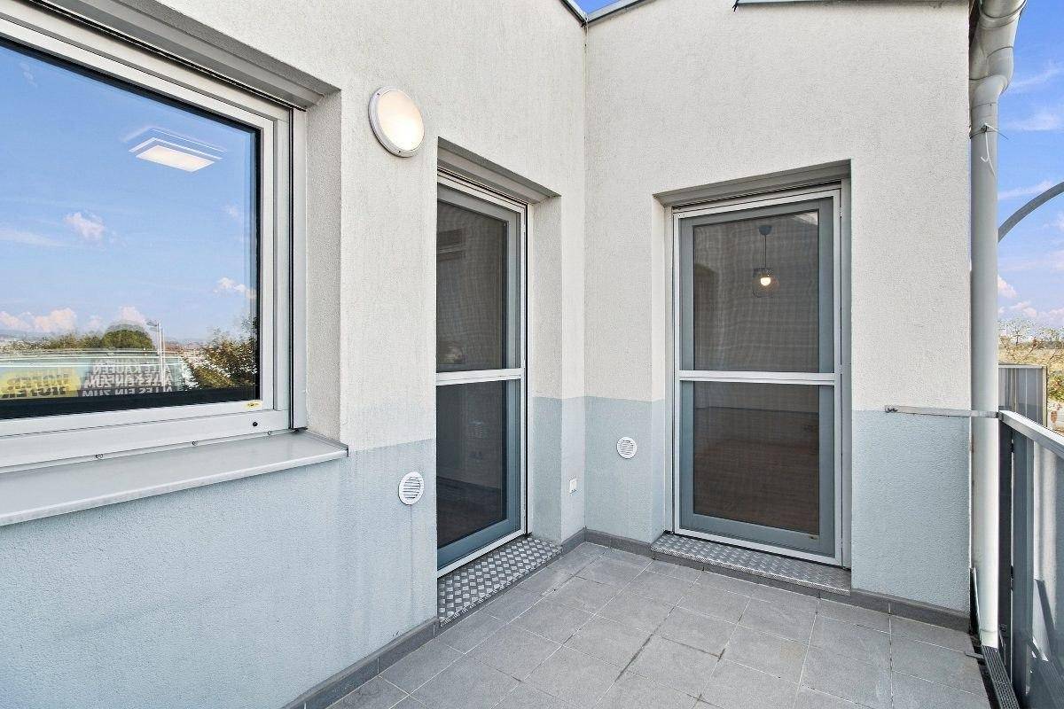 Heller Balkon mit zwei Türen und Fliesenboden, ideal für Entspannung im Freien.