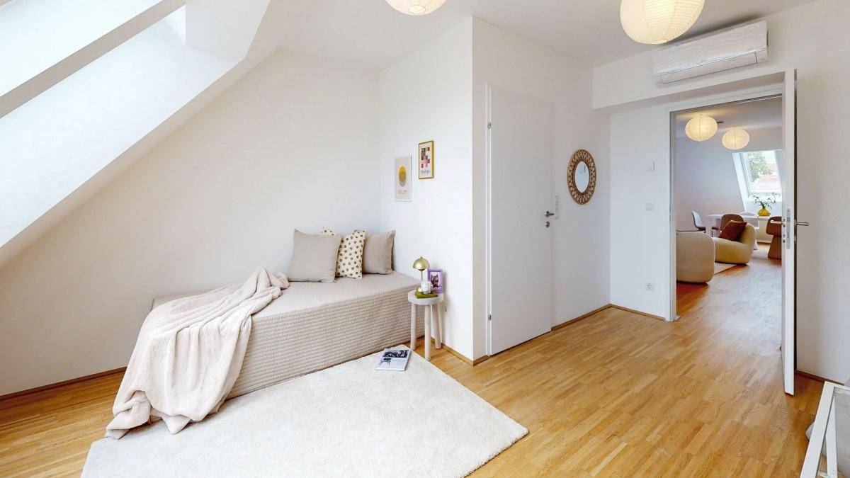 Schlafzimmer mit Dachschrägen, Klimaanlage und Zugang zum offenen Wohnbereich.