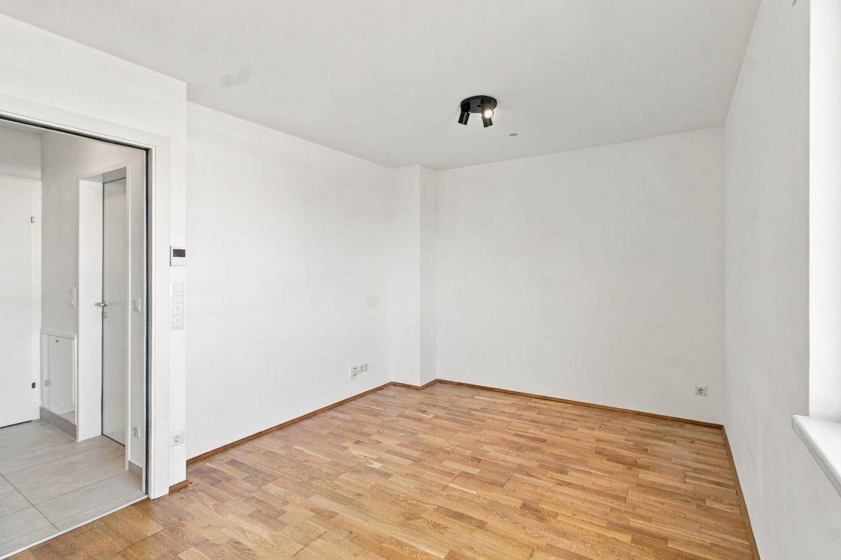 Leeres Wohnzimmer mit hellem Holzboden und weißen Wänden, bereit zur individuellen Gestaltung.