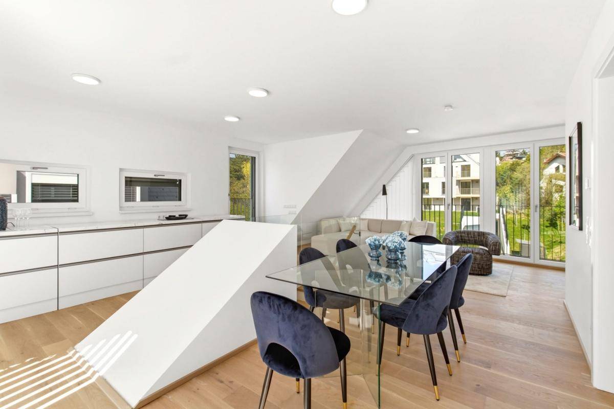 Offener Wohn- und Essbereich mit moderner Küche, Holzboden und Zugang zur Terrasse.