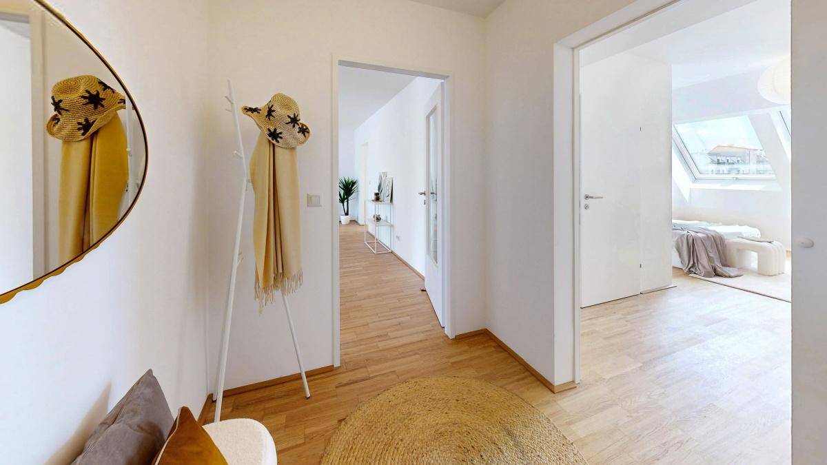 Heller Flur mit Holzfußboden, Spiegel und Zugang zu weiteren Wohnbereichen.