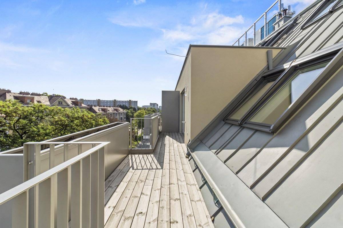 Geräumige Dachterrasse mit Holzboden und Blick auf die umliegende Bebauung.