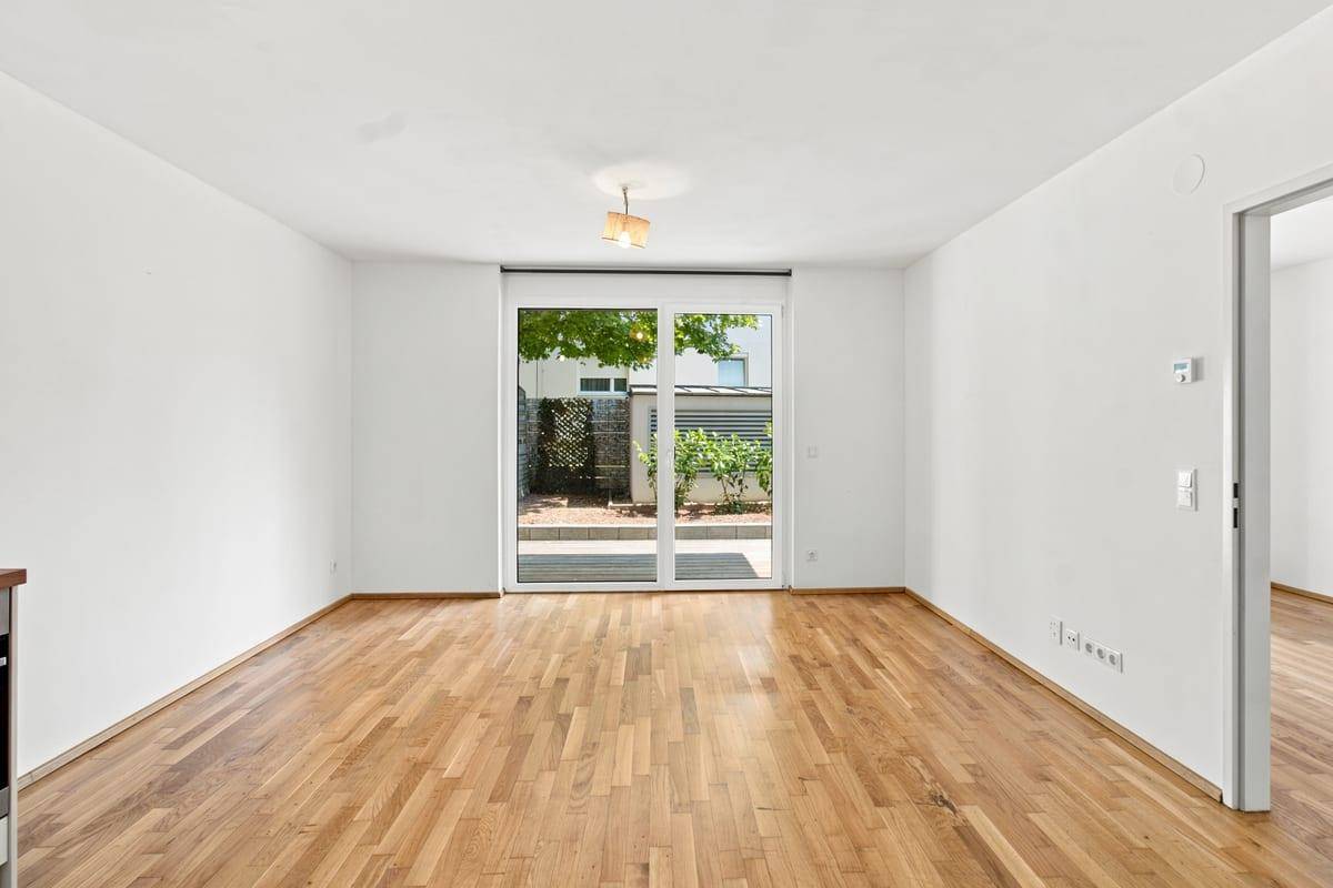 Geräumiges Wohnzimmer mit Holzboden und großen Schiebetüren zum Außenbereich.
