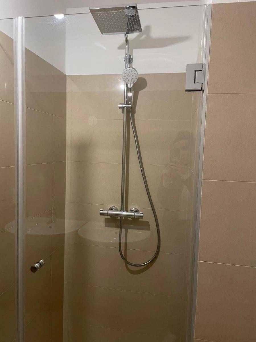 Moderne Duschkabine mit Regendusche und beigefarbenen Fliesen im Badezimmer.