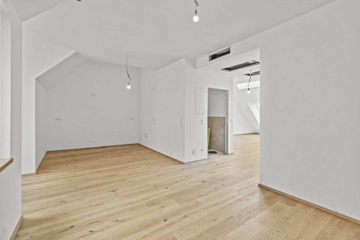 Geräumiger offener Bereich mit Holzboden und weißen Wänden, der vielseitig nutzbar ist.