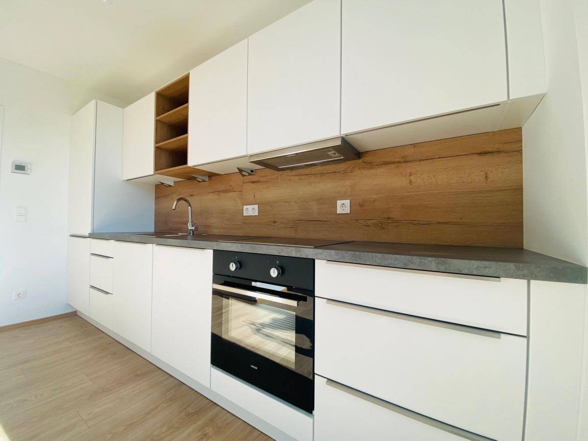 Moderne Einbauküche mit weißen Schränken, Holzakzenten und integrierten Geräten.