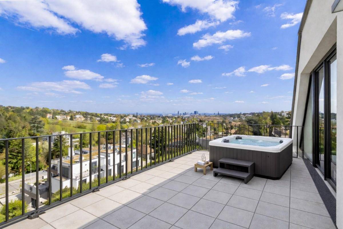 Geräumige Terrasse mit Whirlpool und weitem Blick über die Stadt und die umliegende Landschaft.