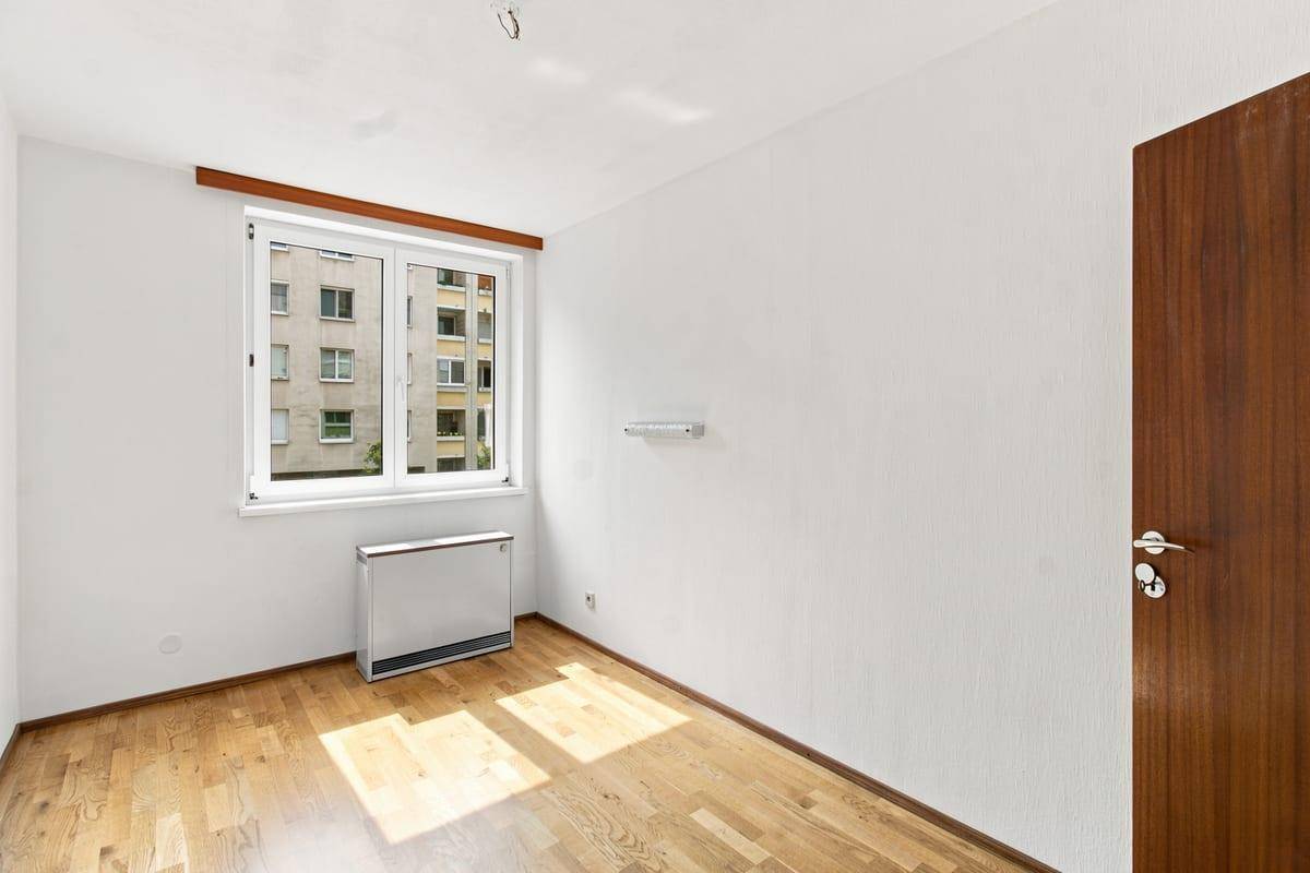 Helles Schlafzimmer mit Holzboden und Fenster, das eine angenehme Atmosphäre schafft.