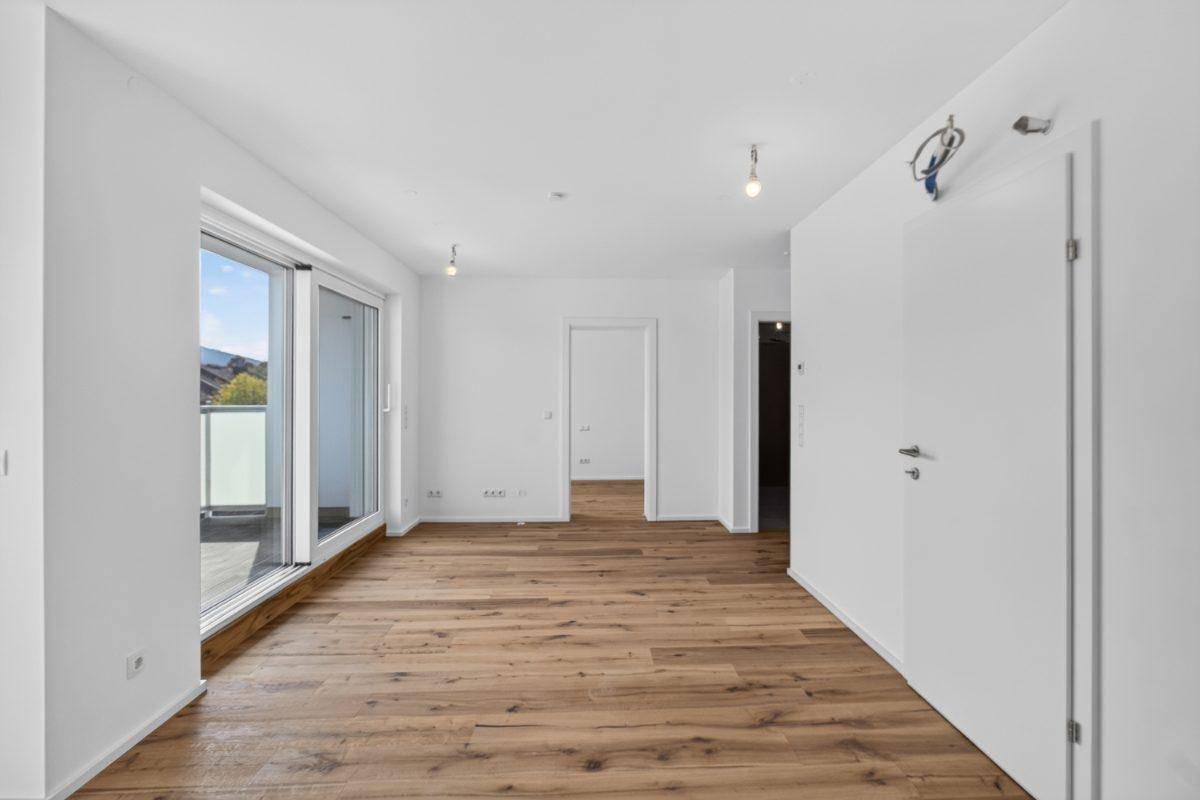 Heller Wohnbereich mit Holzboden und direktem Zugang zu einem Außenbereich.