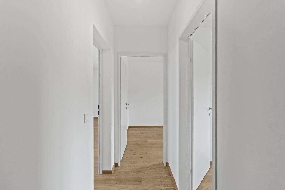 Heller Flur mit Holzboden und mehreren weißen Türen, die zu den angrenzenden Räumen führen.