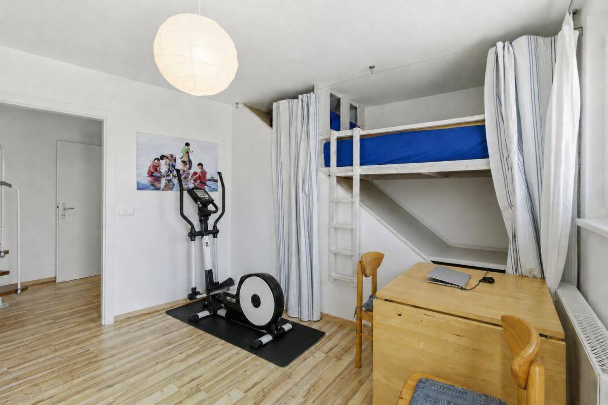 Vielseitiges Zimmer mit Holzboden, Etagenbett, Schreibtisch und einem Fitnessgerät.