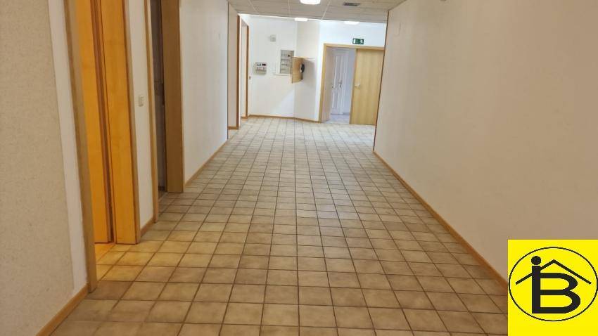 Langer Flur mit Fliesenboden und mehreren Holztüren, der zu verschiedenen Räumen führt.