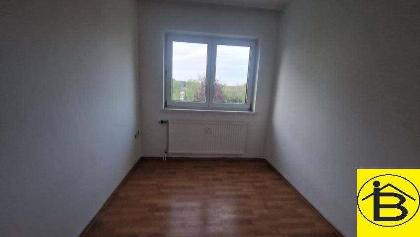 Leeres Zimmer mit Laminatboden und Fenster, bietet vielseitige Nutzungsmöglichkeiten.