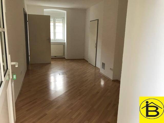 Heller, leerer Raum mit Holzparkettboden und einem Fenster mit Heizkörper darunter, in gutem Zustand.