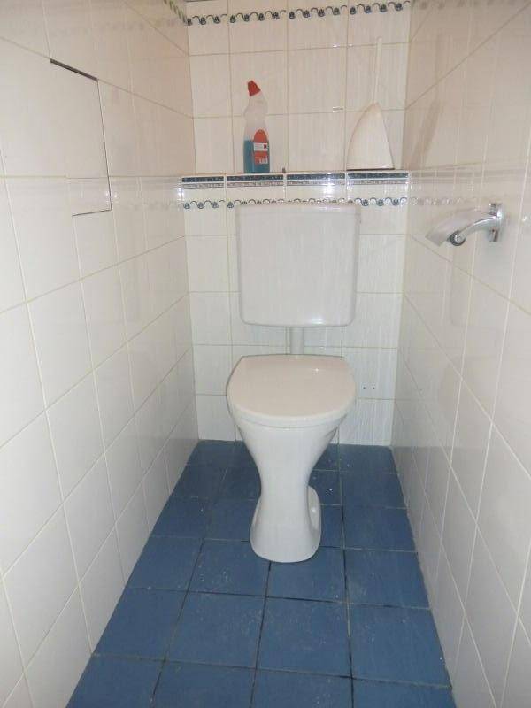 Separates WC mit Toilette, weißen Wandfliesen und blauen Bodenfliesen.