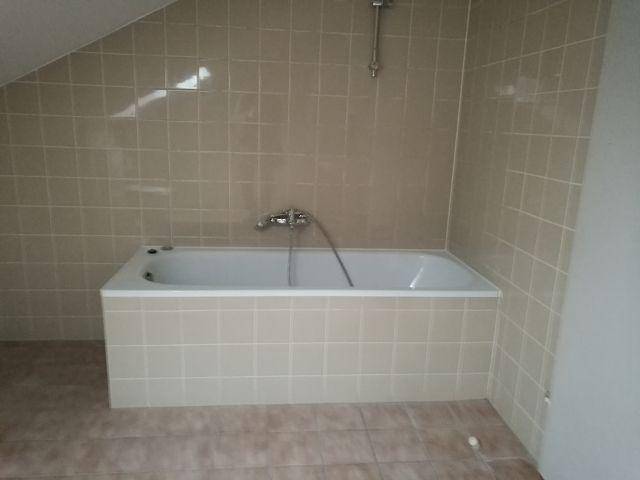 Badezimmer mit Badewanne und beigefarbenen Fliesen an Wänden und Boden.