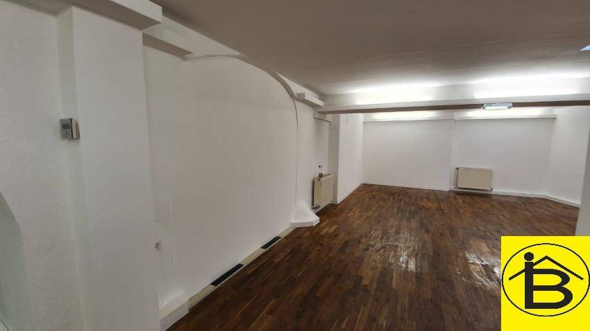 Heller, leerer Raum mit Holzboden, weißen Wänden und einer eleganten geschwungenen Wand.