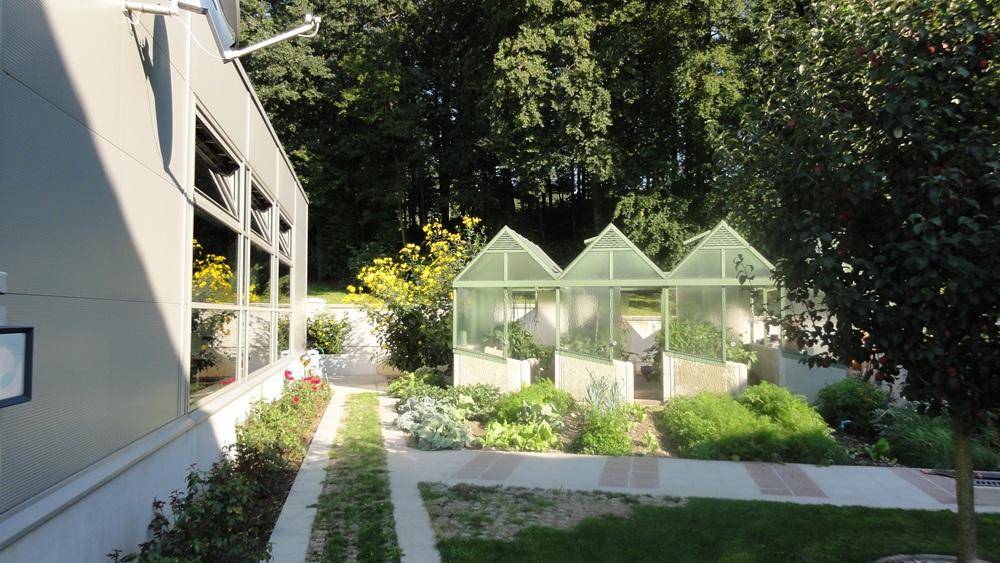 Gartenbereich mit mehreren Gewächshäusern und einem angelegten Küchengarten.