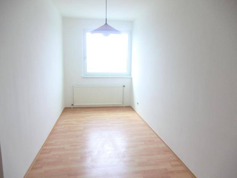 Schmaler Raum mit Laminatboden, weiß gestrichenen Wänden und einem Fenster für natürliches Licht.