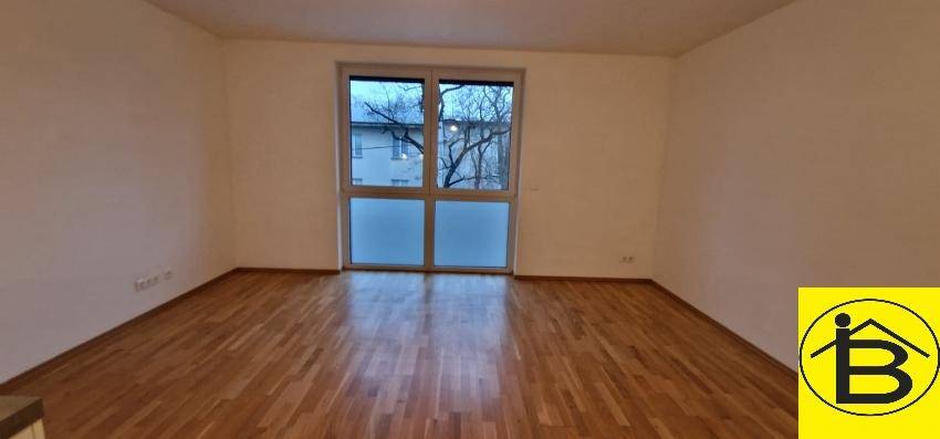 Geräumiger, heller Raum mit großem Fenster und Holzboden, ideal als Wohnzimmer.