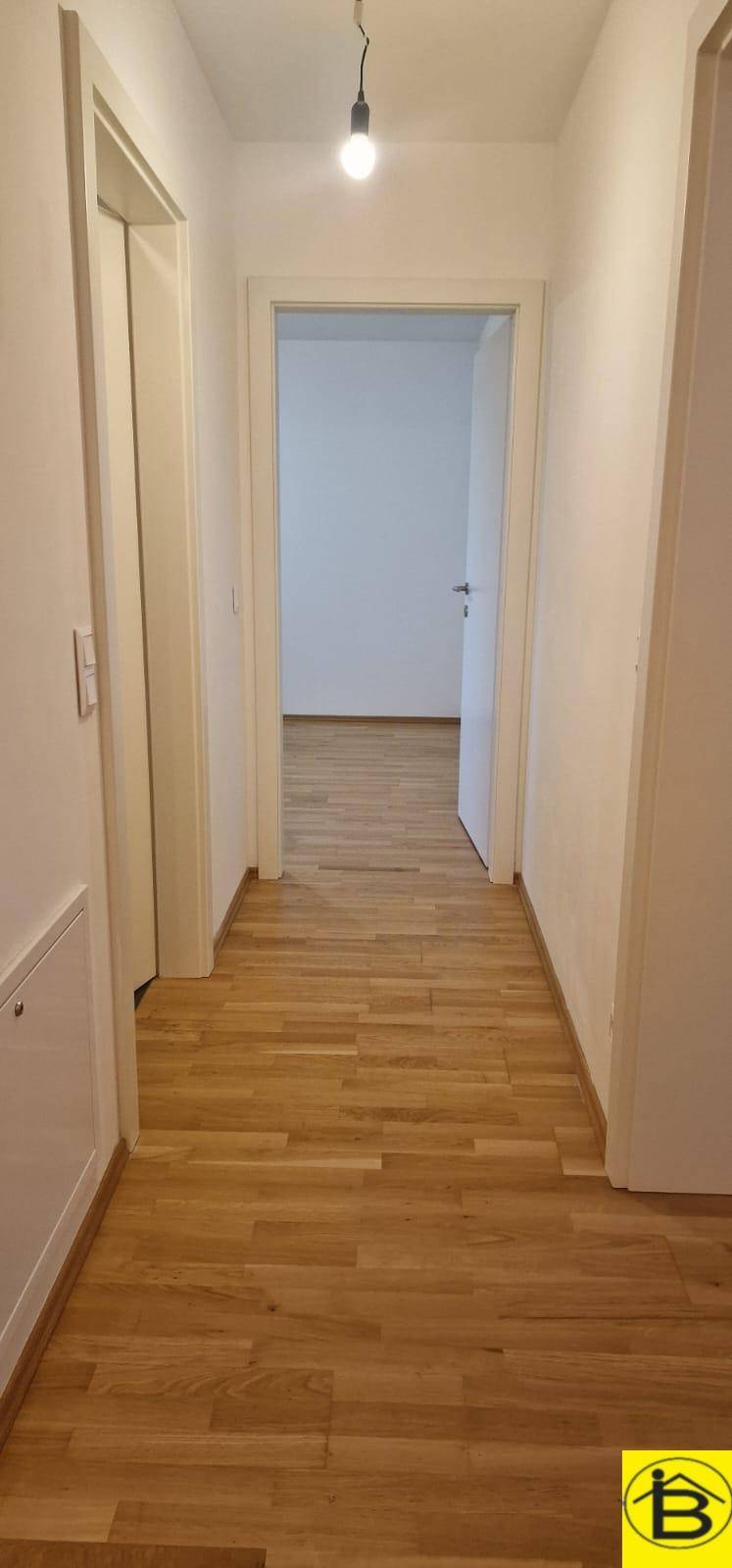 Langer, heller Flur mit Holzboden, der zu verschiedenen Räumen führt.