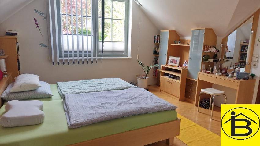 Helles Schlafzimmer mit Holzboden, Schminktisch und Fenster mit Jalousien.