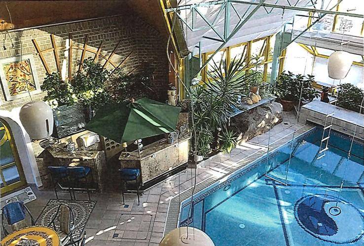 Panoramablick auf den Innenpool mit Bar, Ziegelwänden und üppiger Bepflanzung.