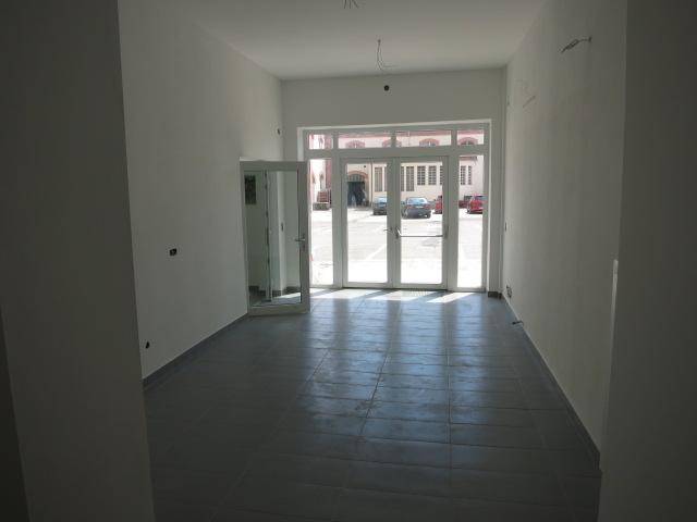 Großer, heller Raum mit breiter Glasfront und Fliesenboden, bietet viel Tageslicht.