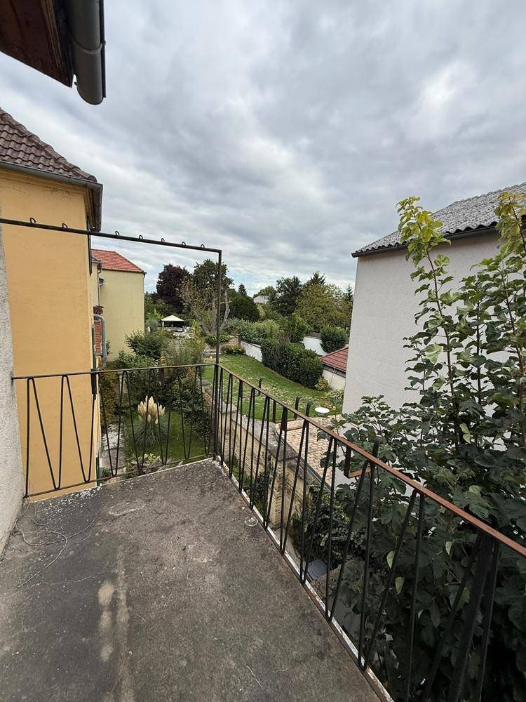 Balkon mit weitem Blick ins Grüne und auf umliegende Gebäude.