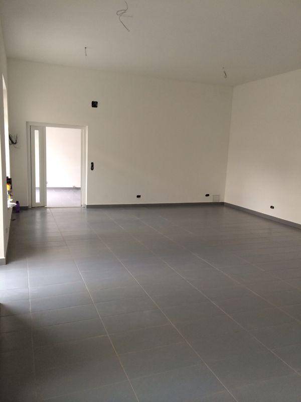 Geräumiger, leerer Innenraum mit Fliesenboden und weiß gestrichenen Wänden, bereit zur Nutzung.