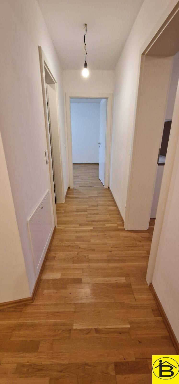 Langer, heller Flur mit Holzboden, der zu verschiedenen Räumen führt.