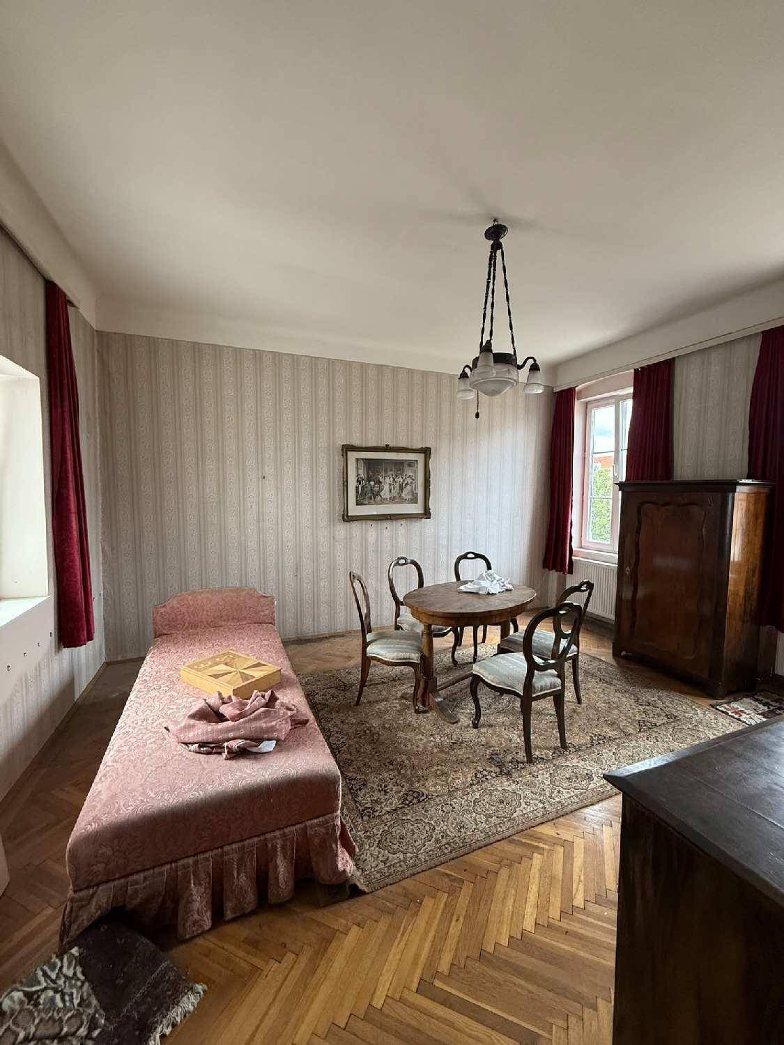Schlafzimmer mit Fischgrätparkett, einem Einzelbett und einem kleinen Esstisch.