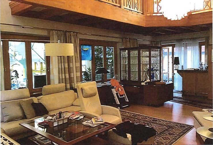 Gemütliches Wohnzimmer mit bequemen Sofas, großen Fenstern und Blick ins Grüne.