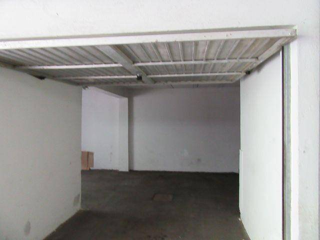 Innenansicht einer leeren Garage mit Betonboden und Metall-Deckenkonstruktion.